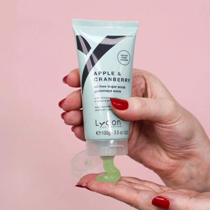 Lycon Apple & Cranberry Sugar Scrub 100g in hand, showcasing oil-free scrub with green texture on a pink background.