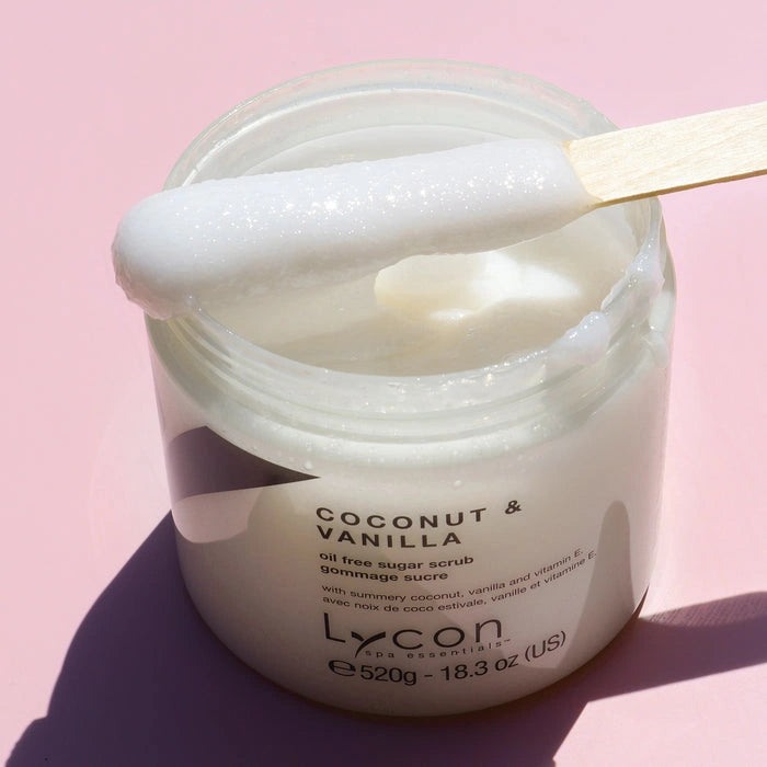 Lycon Coconut & Vanilla Sugar Scrub 520g in jar with creamy scrub and spatula on pink background