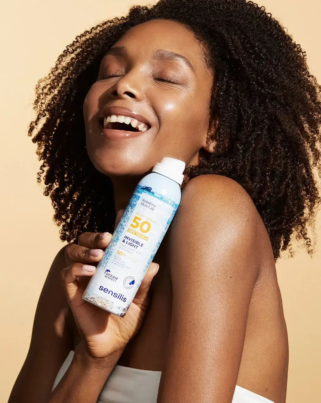 Sensilis Body Spray 50 Dry Touch 200ml met een lachende vrouw, ideaal voor een plakkerloze zonnebescherming.
