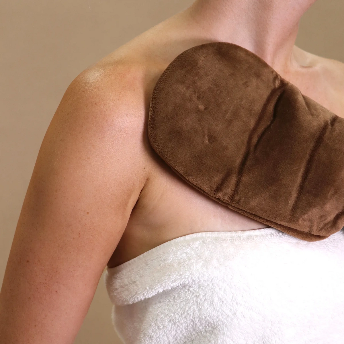 Lyco-Bronze Application Mitt voor een streep-vrije zelfbruining, geplaatst op de schouder, zachte en comfortabele textuur.