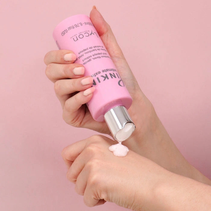 Lycon Pinkini Intimate Exfoliant 200ml met een zachte, rozenkleurige textuur op hand vlak tegen een roze achtergrond.