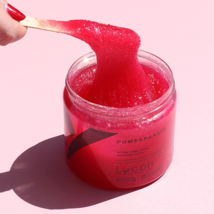 Lycon Pomegranate Sugar Scrub 520g met een helderroze scrub op een spatel en in een jar, perfect voor de rijpere huid.