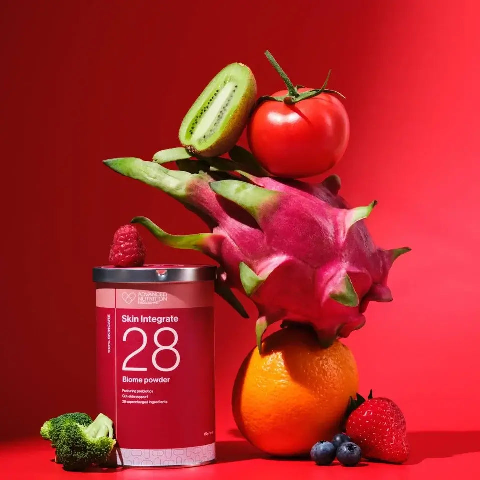 Skin Integrate 28 Biome Powder Advanced Nutrition Programme 150g met kleurrijke verse groenten en fruit op een rode achtergrond.
